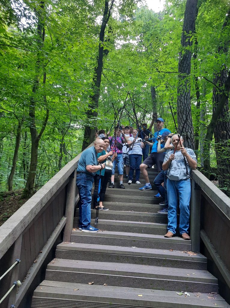 Kilka osób stoi na schodach, wokół las