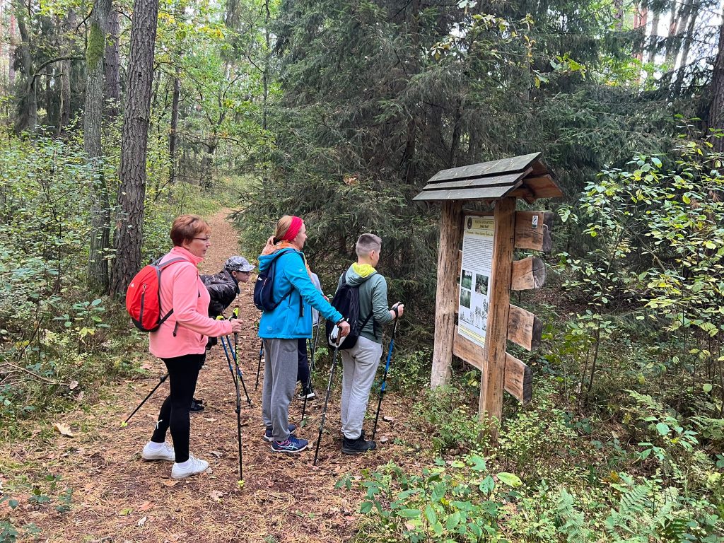 Grupa ogląda tablicę informacyjną w lesie