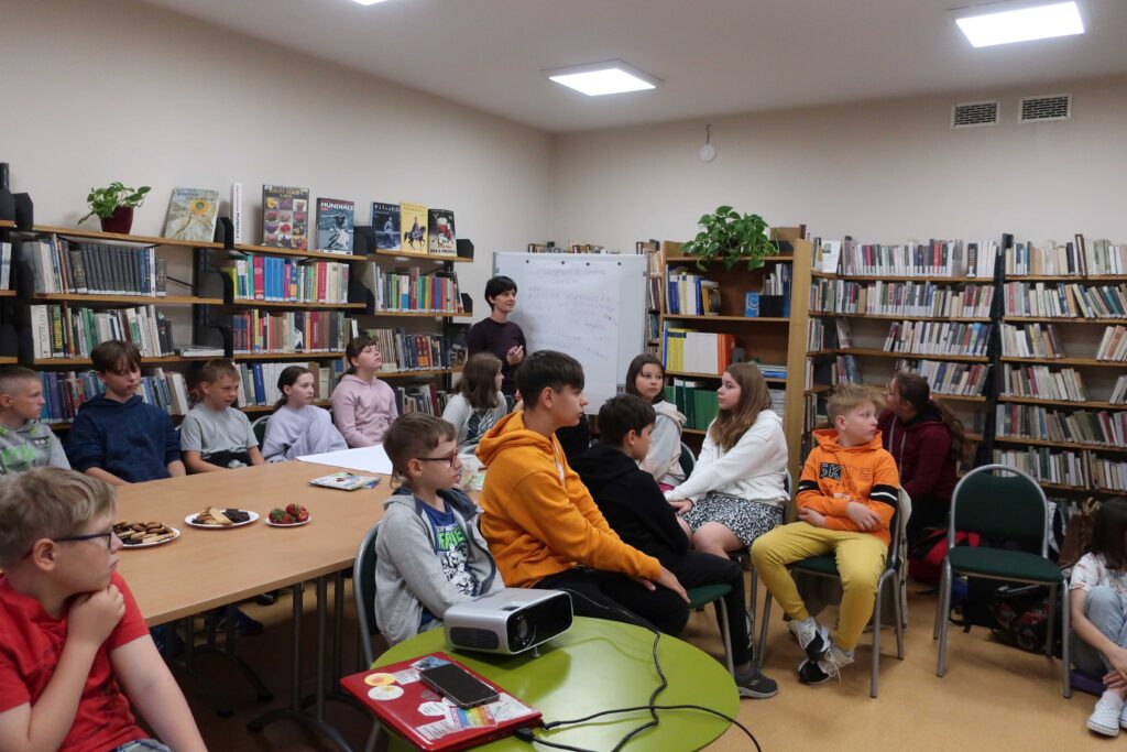 Młodzież siedzi i słucha wykładu w bibliotece