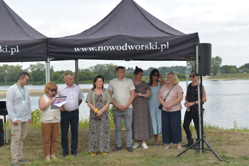 8 osób stoi pod namiotem nad rzeką