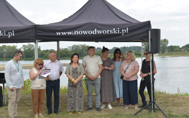 8 osób stoi pod namiotem nad rzeką