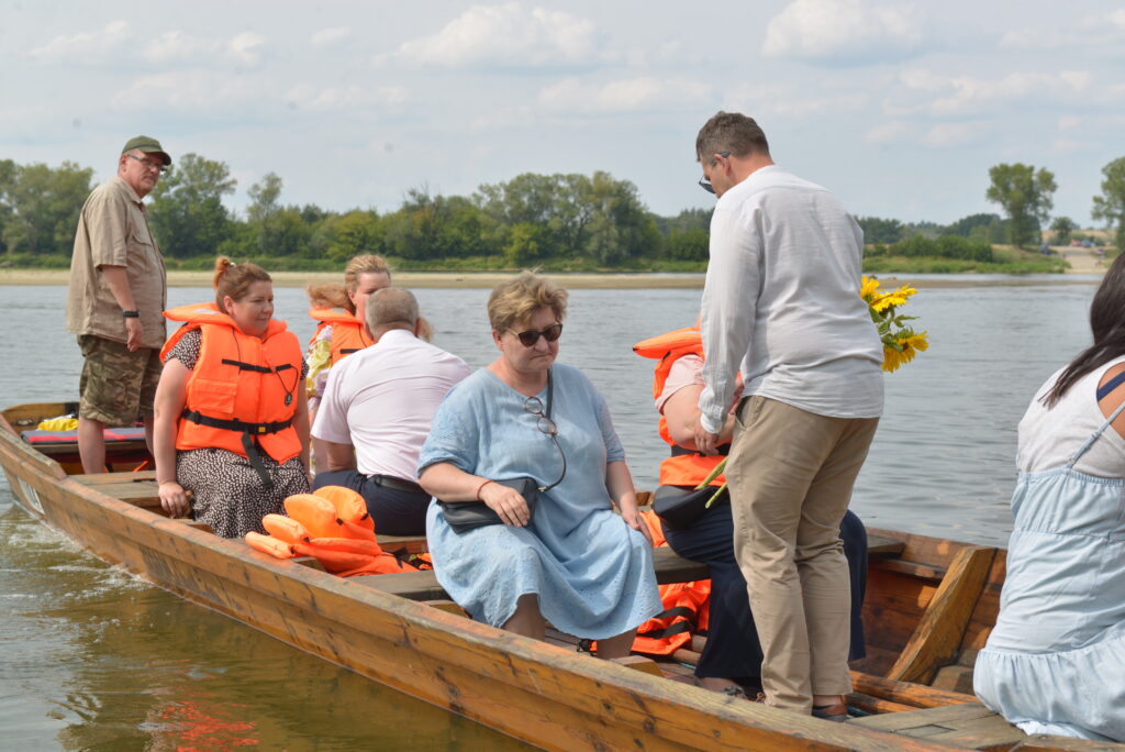 6 osób pływa łodzią po rzece